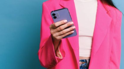 joven con chaqueta rosa sujetando un iPhone
